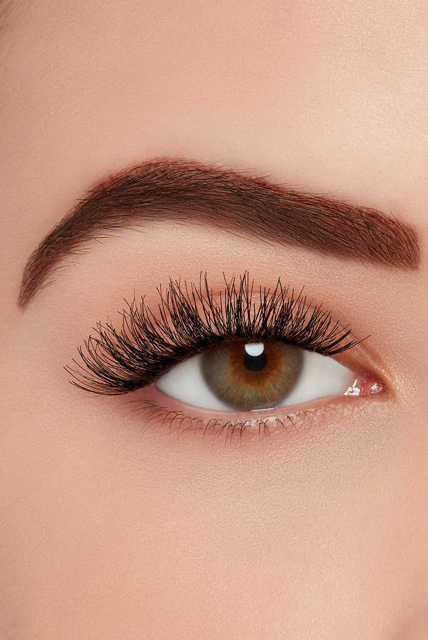 Close-up of eye with Ardell strip lashes, showcasing full, wispy volume and natural curl on a brown-eyed model.