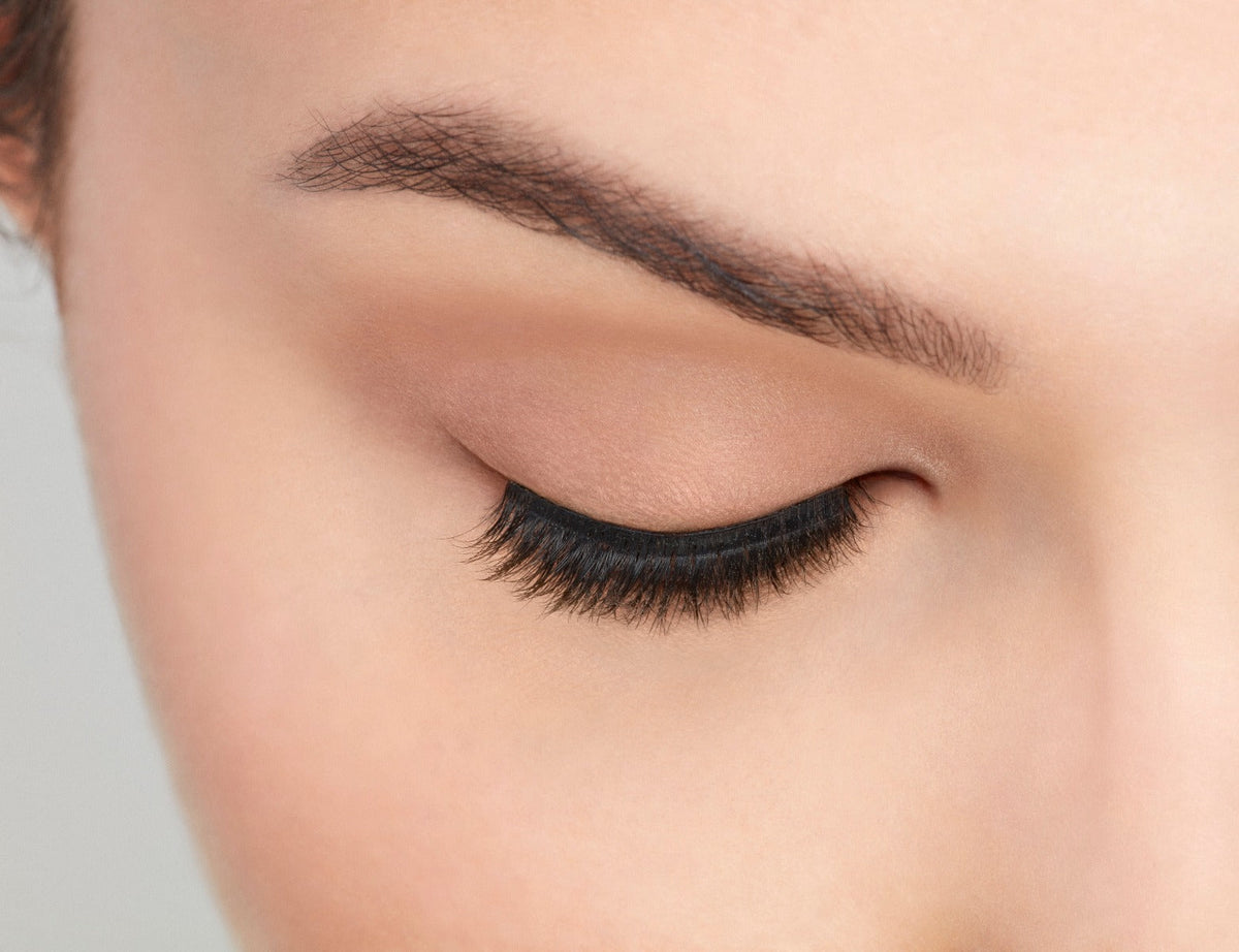 An extreme front shot of closed eye wearing a Fauxmink 815 by Ardell creating a natural, elongated & curly lash