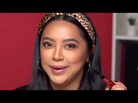 Model wearing leopard headband applies mascara with radiant glam makeup.